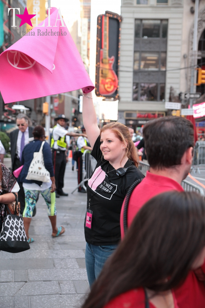 Девушка с розовым ковриком машет для того, чтобы учасники лучше видели - где вход:)